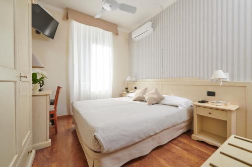 a bedroom with a white bed and a television at Hotel Villa Aurora in Lezzeno