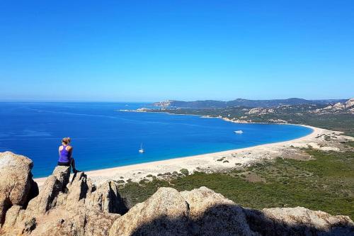 a woman sitting on a rock overlooking a beach at L'Original, Superbe appartement à 5min de la plage in Zonza
