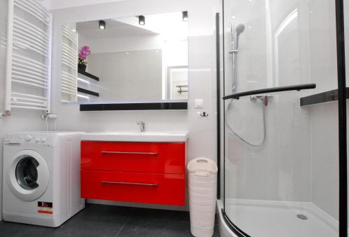 y baño con lavabo rojo y lavadora. en Apartament DIAMENTOWY z garażem -Centrum Gliwic, en Gliwice