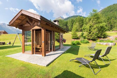 a small cabin in a field with two chairs at Chalet Rosita in Livigno