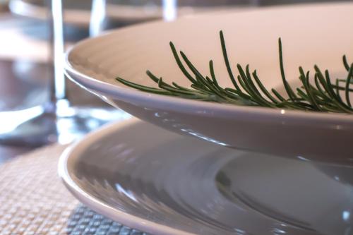 a white bowl with a sprig of rosemary on a table at Torre Granitola Suite in Granitola