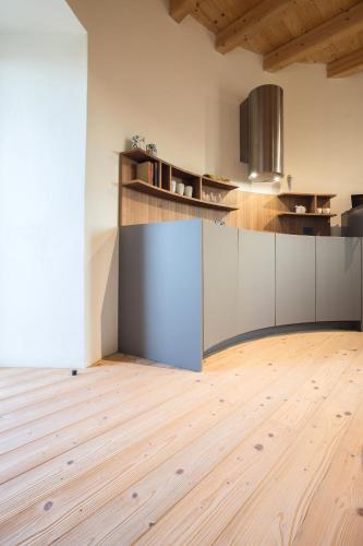 a kitchen with white cabinets and a wooden floor at Torre Granitola Suite in Granitola