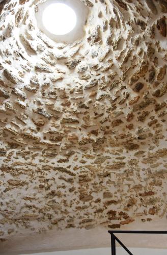 a ceiling in a room with a stone wall at Torre Granitola Suite in Granitola
