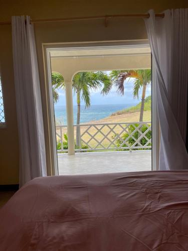 a bedroom with a view of the ocean through a window at ‘MAYARO’ Private Room with Ocean View in Saint Philip