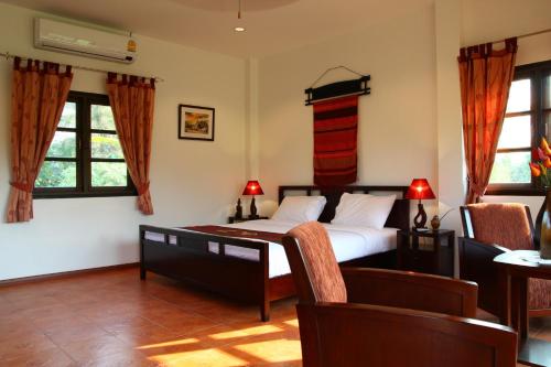 a bedroom with a bed and two windows at Mai Siam Resort in Mae On