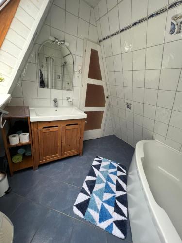 ein Badezimmer mit einem Waschbecken, einer Badewanne und einem Spiegel in der Unterkunft Haus Luzia in Meschede