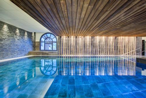 - une piscine avec du carrelage bleu et un plafond en bois dans l'établissement La Cordee 623-Luxury apartment with mountain view and SPA, à Chamonix-Mont-Blanc