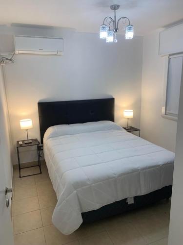 a bedroom with a bed with two lamps on two tables at Dpto Lyon in General Roca