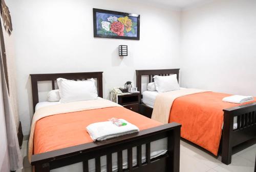 a bedroom with two beds with orange sheets at Pasola Guest House in Medan