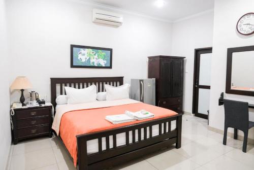een slaapkamer met een bed, een bureau en een televisie bij Pasola Guest House in Medan