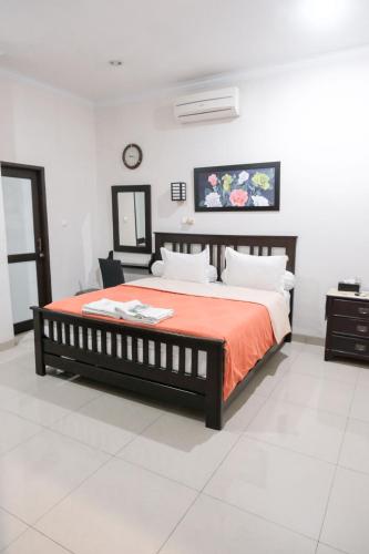 a bedroom with a bed with a orange blanket and a clock at Pasola Guest House in Medan