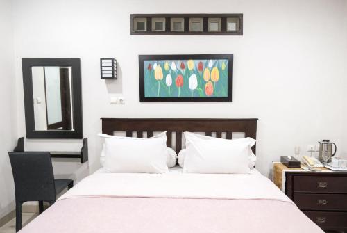 a bedroom with a bed with a desk and a painting on the wall at Pasola Guest House in Medan