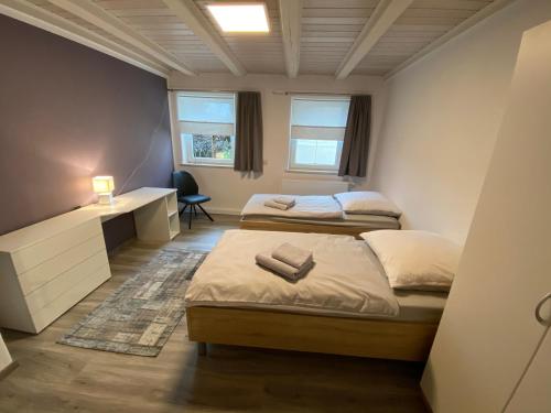 twee bedden in een kleine kamer met een bureau en een bed sidx sidx sidx sidx bij Gästezimmer Kirchdorf in Unteropfingen