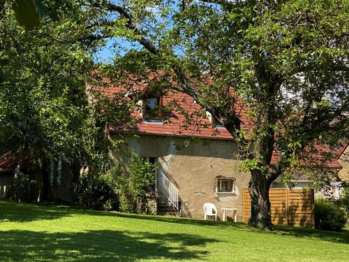 une maison avec deux chaises blanches dans une cour dans l'établissement Domaine Les Bertrands, à Couches