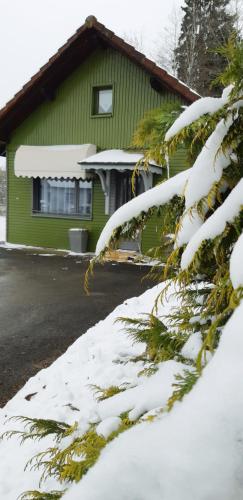 una casa verde con la neve sul lato di Gîte le chalet vert , prêt de raquettes a Frambouhans