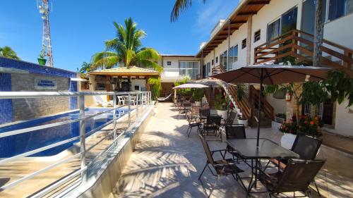 a balcony with tables and chairs and a swimming pool at Barreto Hospedagem in Caraguatatuba