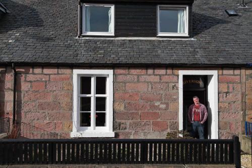 a man standing in a window of a brick building at Riverside Cottage City Centre in Inverness