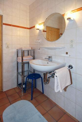 a bathroom with a sink and a mirror and a stool at Ferienwohnung Taubenschlag in Werdum