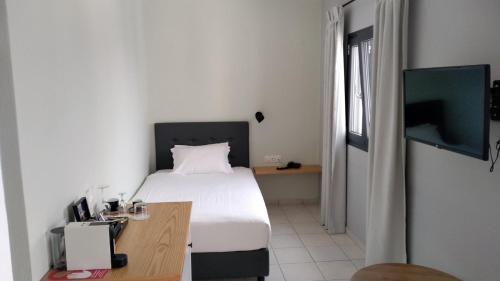 a bedroom with a bed and a desk and a television at Minois Boutique Hotel in Stalida