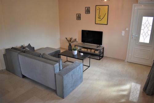 ein Wohnzimmer mit einem Sofa und einem TV in der Unterkunft Christina's apartment in Kontokali