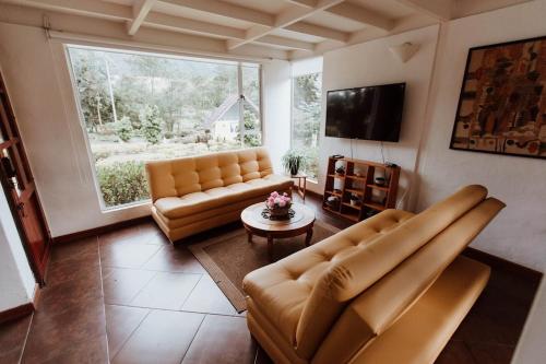 a living room with two leather couches and a large window at Chalet Andino Sesquile in Suesca