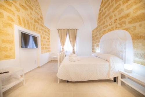 een witte slaapkamer met een bed en een televisie bij Antiche Dimore in Mazara del Vallo
