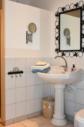 une salle de bain blanche avec un lavabo et un miroir dans l'établissement La Farigoule, à Berrias Et Casteljau