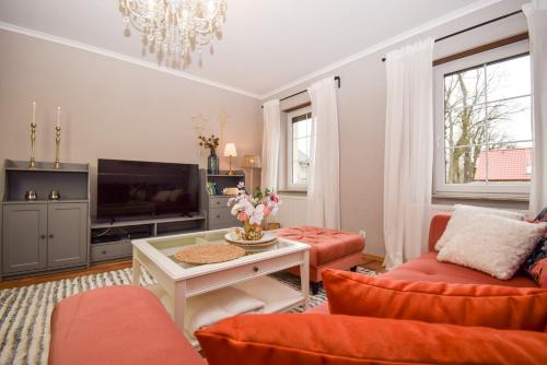 a living room with orange furniture and a tv at Apartament Maciej in Żary