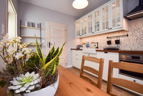 a kitchen with white cabinets and a vase of flowers at Apartament Maciej in Żary