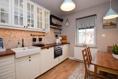 a kitchen with white cabinets and a wooden table at Apartament Maciej in Żary