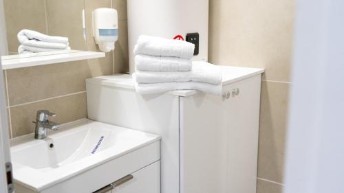 a bathroom with a stack of towels and a sink at Sea View Apartments Olimp - Avenue Hotels in Olimp