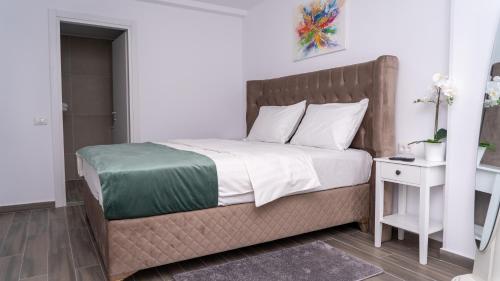 a bedroom with a large bed and a nightstand with a bed sidx sidx sidx at Sea View Apartments Olimp - Avenue Hotels in Olimp