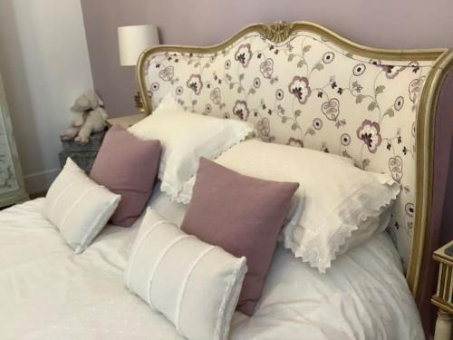 a bed with white and purple pillows on it at Lovely 1 bed flat in Victorian house 300m seafront in Penzance
