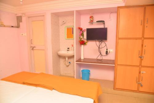 Habitación con cama, lavabo y TV. en bk residency, en Khammam