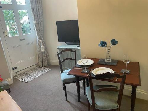 een woonkamer met een tafel en een bureau met stoelen bij Lovely 1 bed flat in Victorian house 300m seafront in Penzance