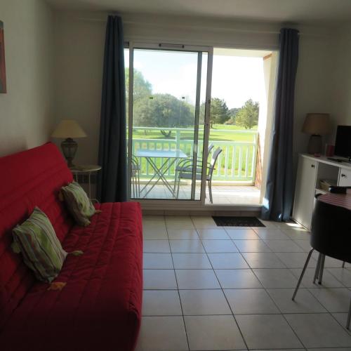 a living room with a red couch and a balcony at Studio Pornic Golf avec piscine, 7 nuits mini, 2 personnes in Pornic