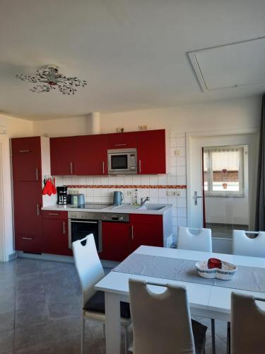een keuken met rode kasten en een tafel en stoelen bij Ferienwohnung Ostrau in Bad Schandau