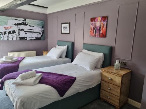 two beds in a small room with purple walls at The Plough Inn in Marsham