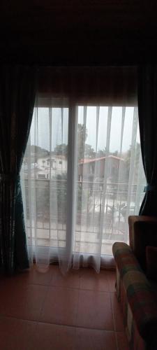 a living room with a window with white curtains at Rosemary Pansiyon in Cıralı