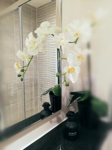 a vase filled with white flowers in a window at Executive Apartment nr NEC, BP Pulse Live, Hampton In Arden in Hampton in Arden