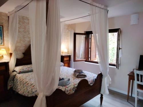 a bedroom with a canopy bed with white curtains at Sguardo sul lago in Trevignano Romano