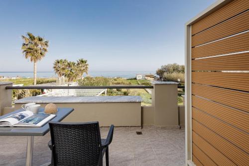 balcón con mesa, sillas y vistas al océano en Yiannis Apartments, en Adelianos Kampos