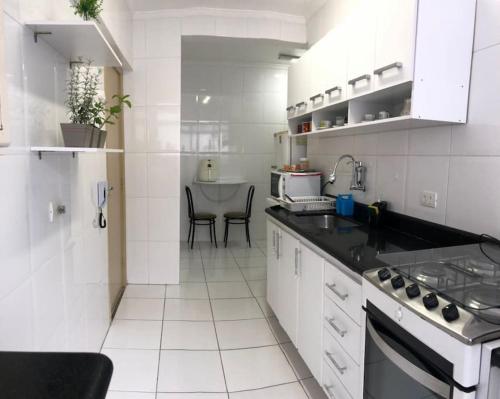 a white kitchen with a sink and a stove at Apartamento quadra da praia - Pitangueiras Guarujá in Guarujá