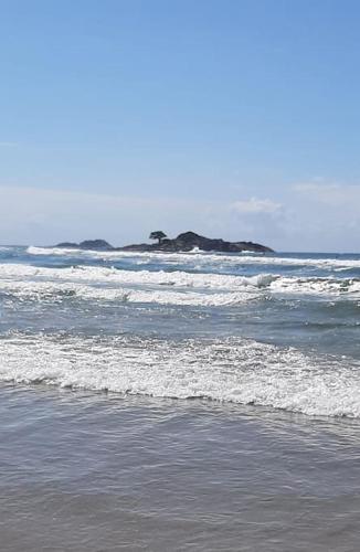 a beach with waves and rocks in the ocean at Apartamento quadra da praia - Pitangueiras Guarujá in Guarujá