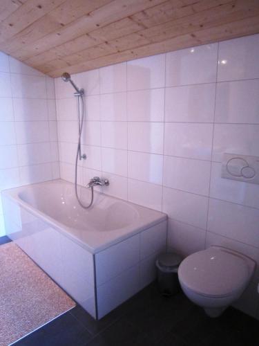 a white bathroom with a tub and a toilet at Studio Bergblick in Mellau
