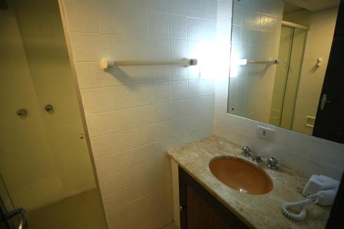 ein Bad mit einem Waschbecken und einem Spiegel in der Unterkunft Essência Hotel Pato Branco in Pato Branco