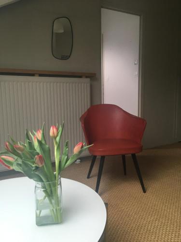 um vaso de flores sobre uma mesa ao lado de uma cadeira vermelha em Appartement cosy et lumineux em Nantes