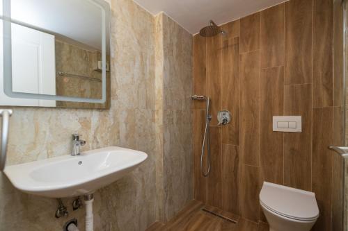W łazience znajduje się umywalka, toaleta i lustro. w obiekcie Ventus Hotel w mieście Ksamil