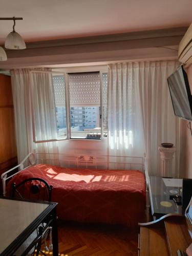 un dormitorio con una cama y una ventana en Hosp Italiano cómodo equipado con piano luz y sol Bienvenidos!, en Buenos Aires