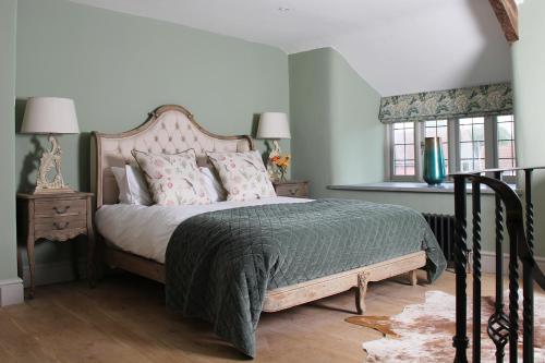 Bramley Cottage at Stepps House في Broadway: غرفة نوم مع سرير كبير مع وسائد وردية